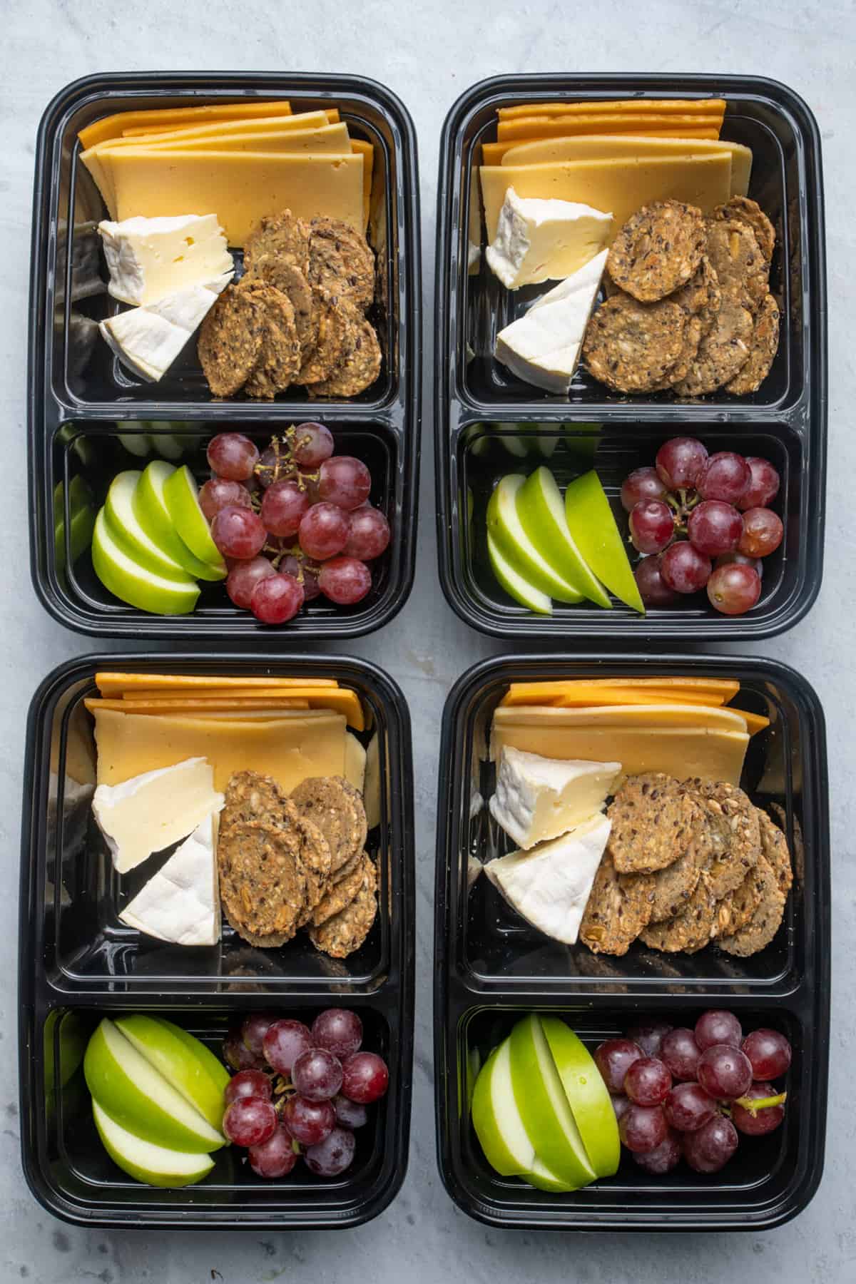 Meal prep containers with cheese, fruit and crackers