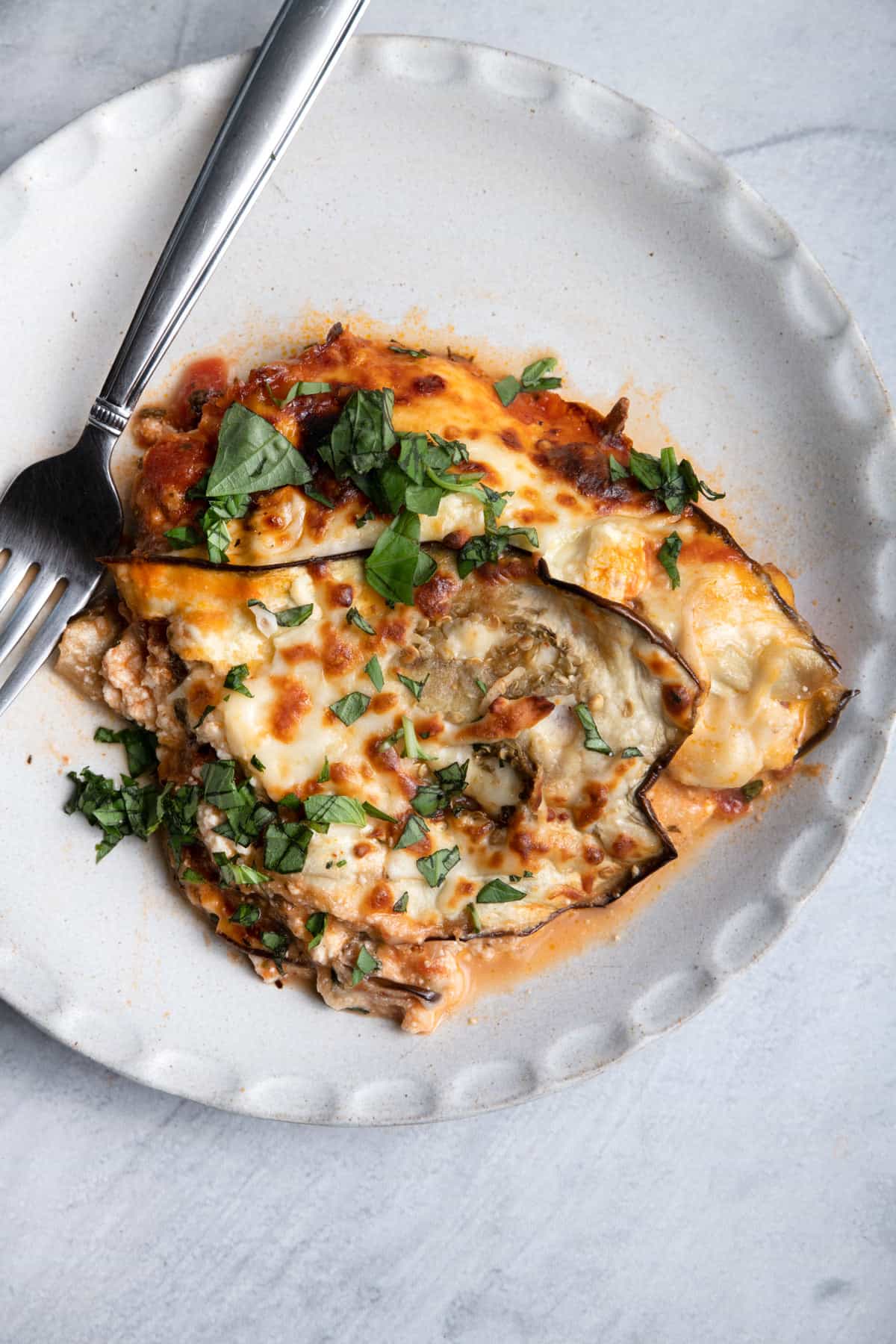 Slice of eggplant lasagna on a plate with a fork