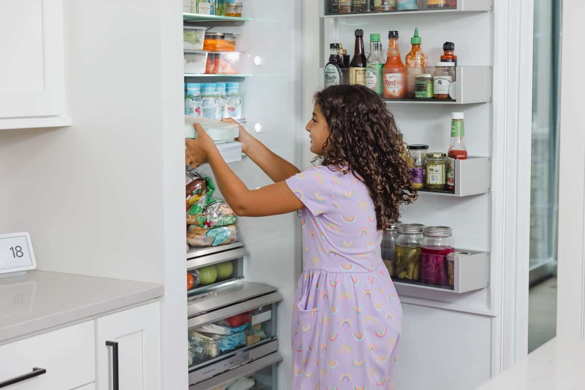 Carine putting away lunchbox in fridge