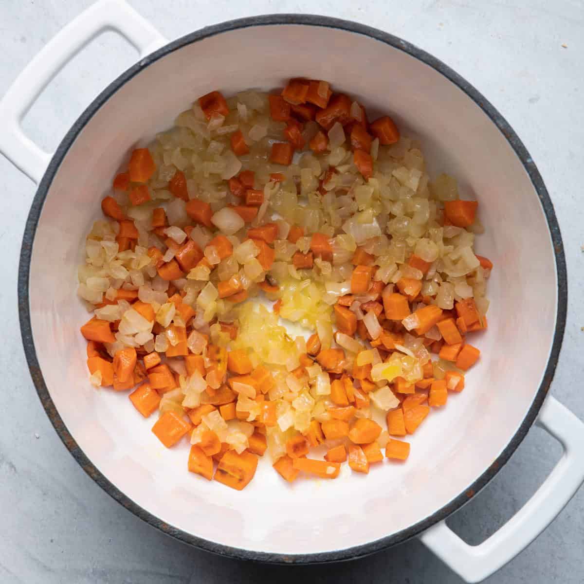 Pot with cooked onions and carrots.