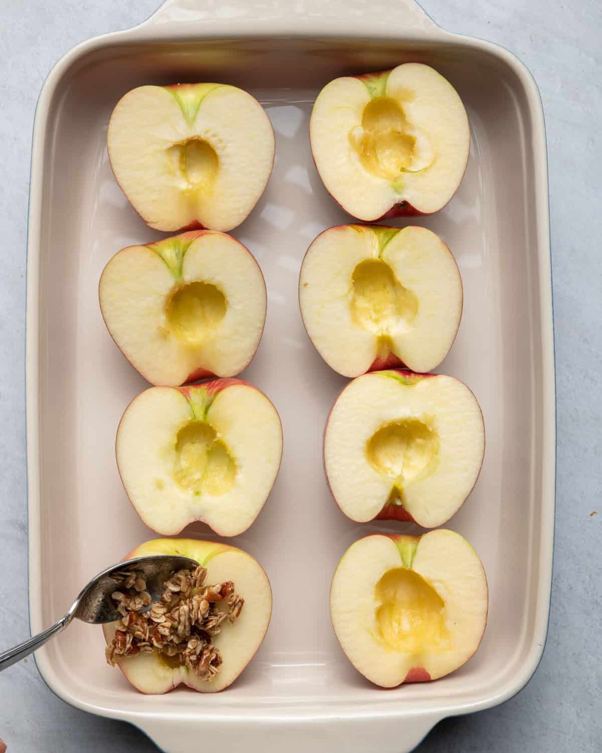 Scooping stuffing into the apples.