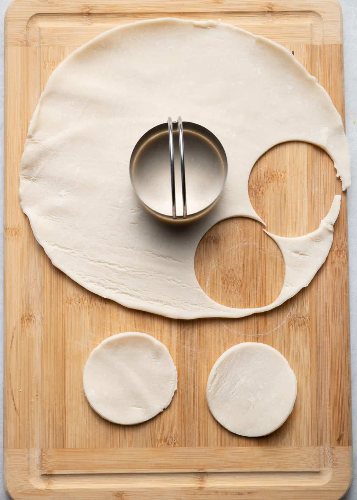 Rolled out dough, round cookie cutter cutting out circle.