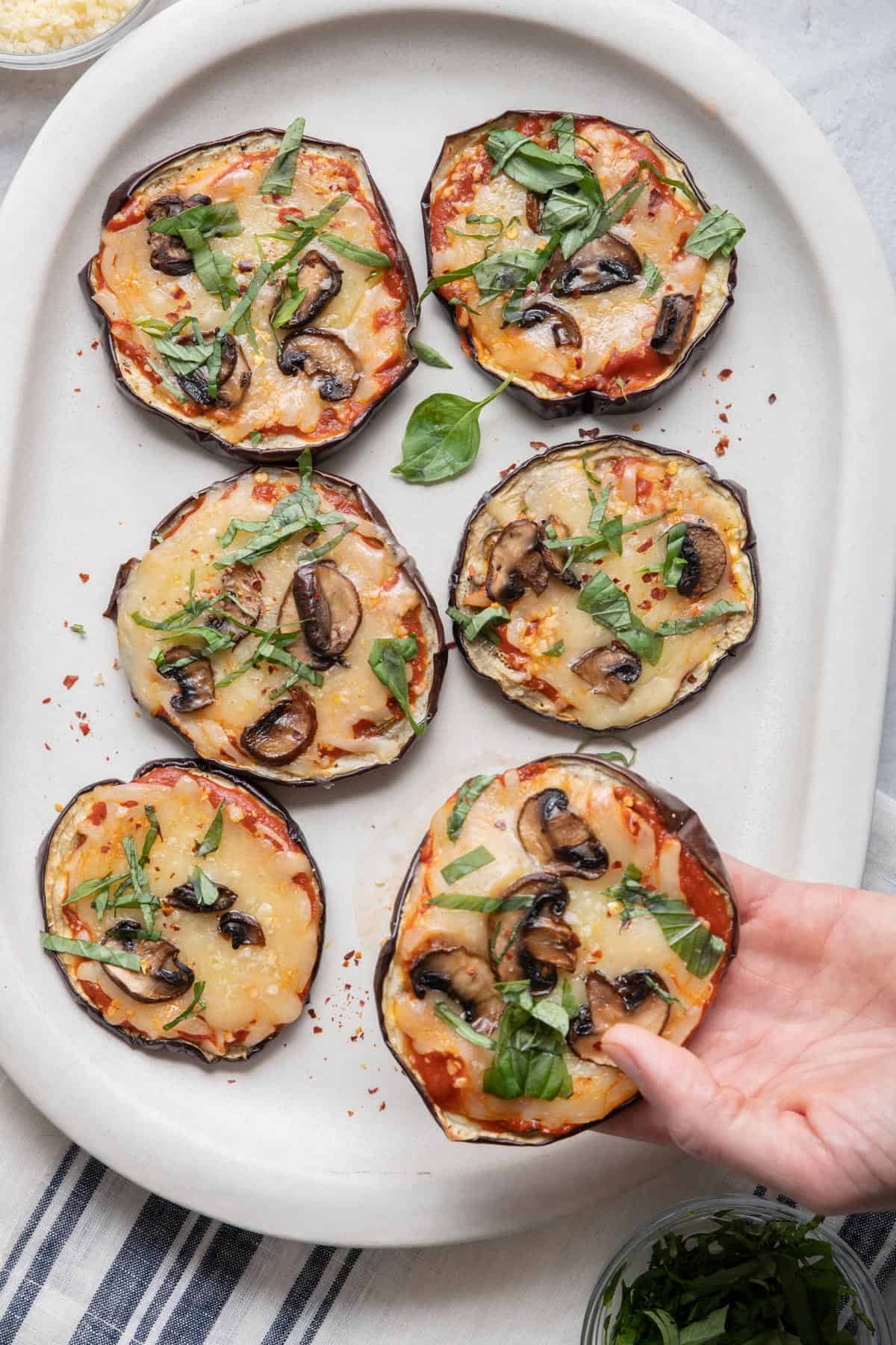 Hand holding one eggplant pizza