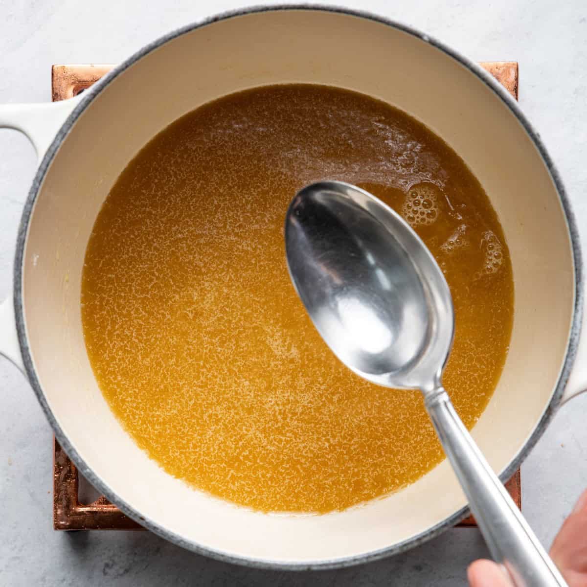 Spoon adding water to drippings.