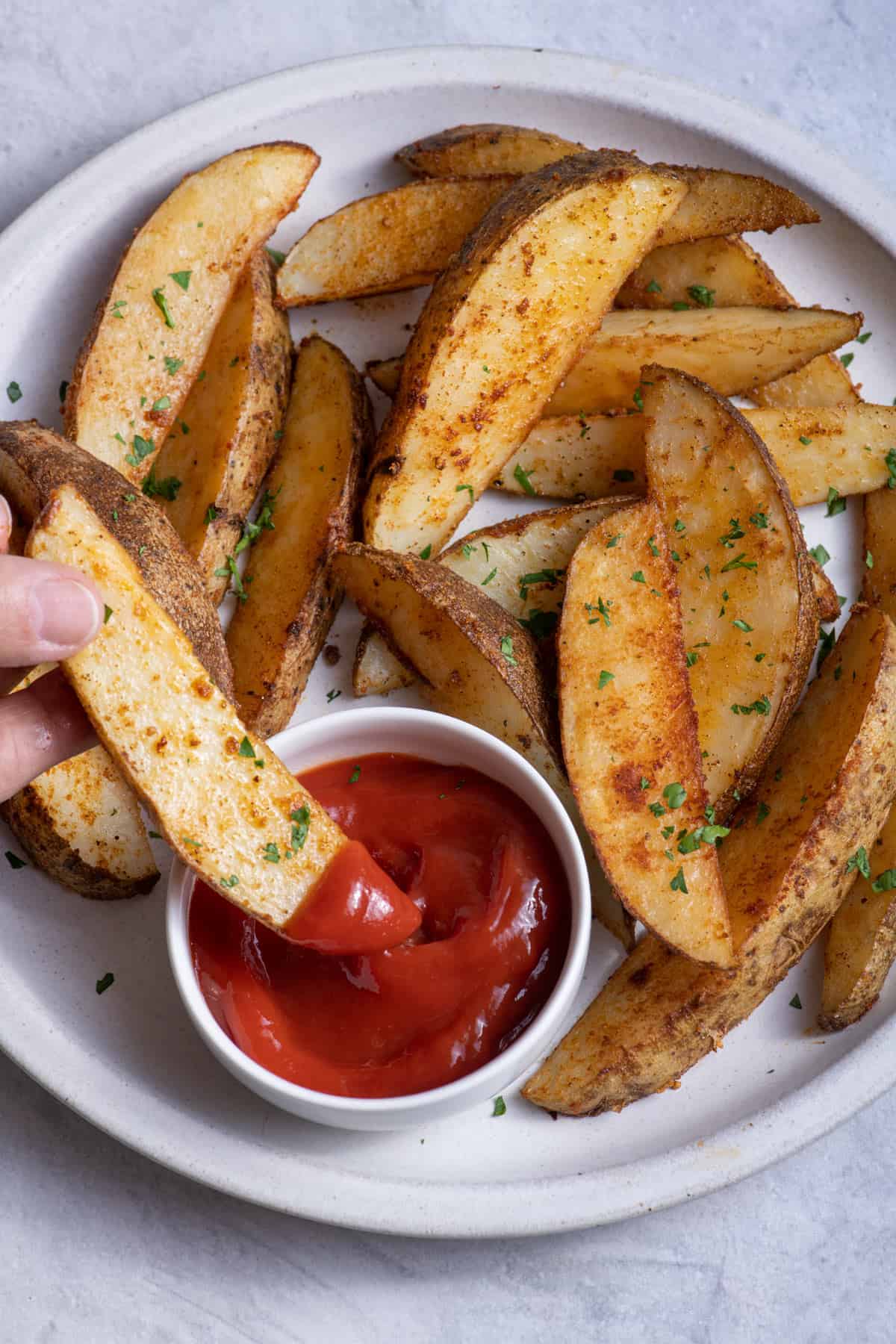 Dunking baked potato wedge into ketchup
