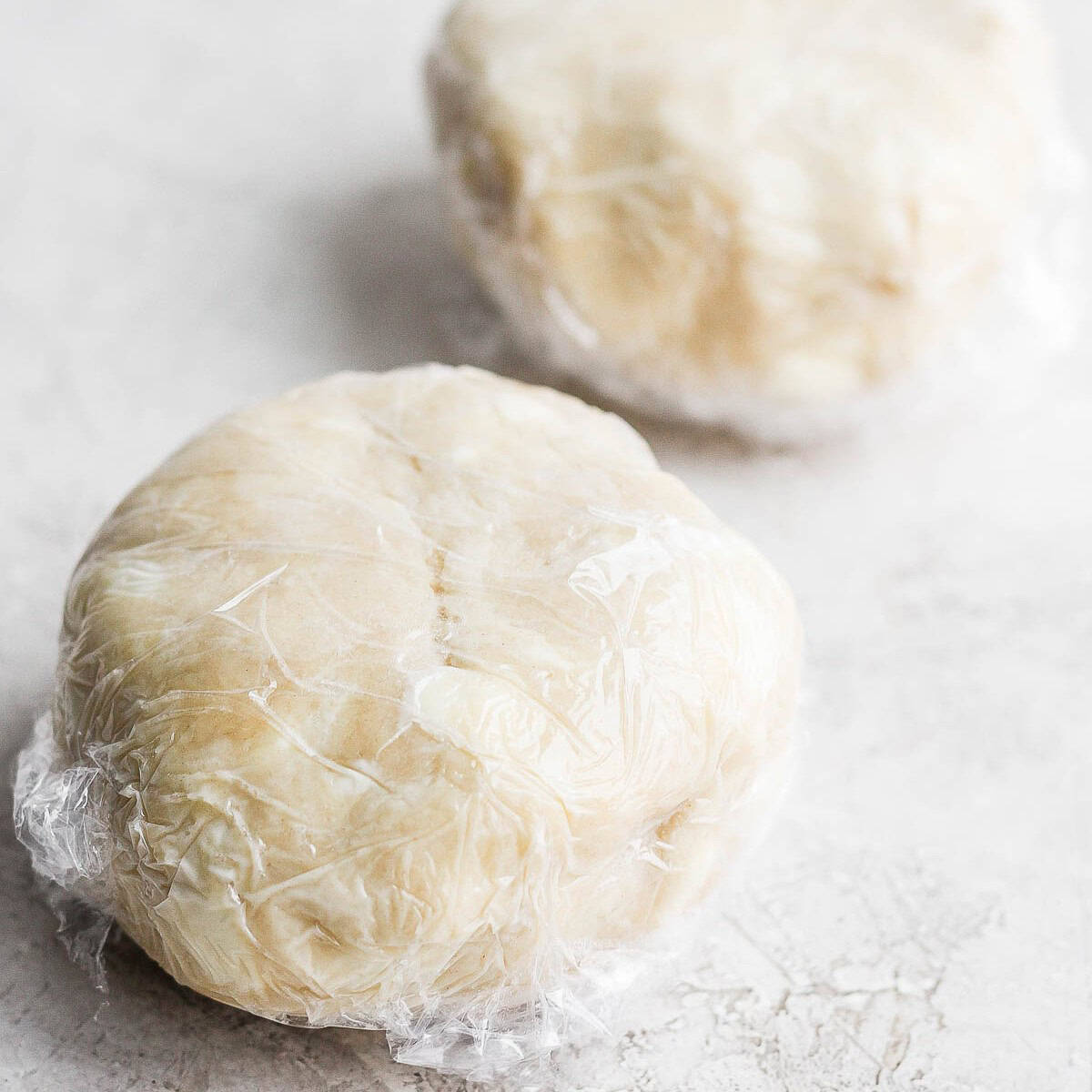 Two dough balls wrapped in plastic.