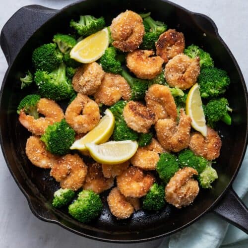 Sesame shrimp with broccoli and lemon wedges on skillet