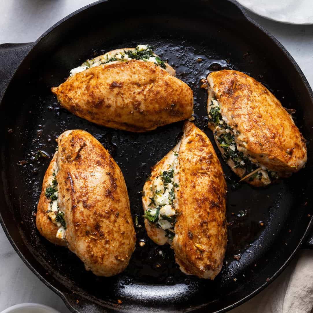 4 stuffed chicken breasts on skillet after cooked.