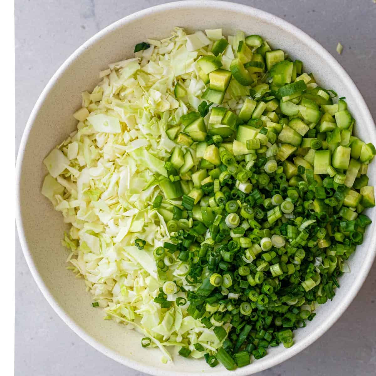 All of the green goddess salad ingredients inside of a bowl before adding the dressing.