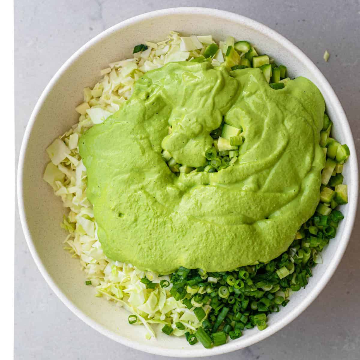 Adding the green goddess salad dressing on top of the salad.