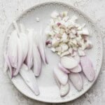 Three types of cut up shallots on a plate.