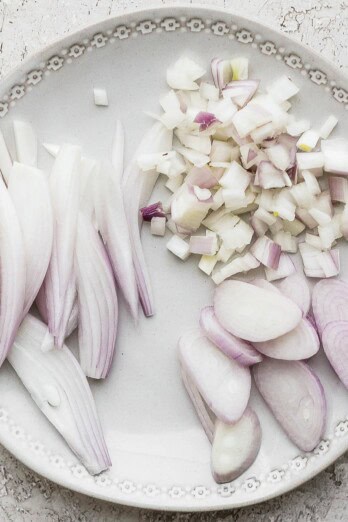 Three types of cut up shallots on a plate.