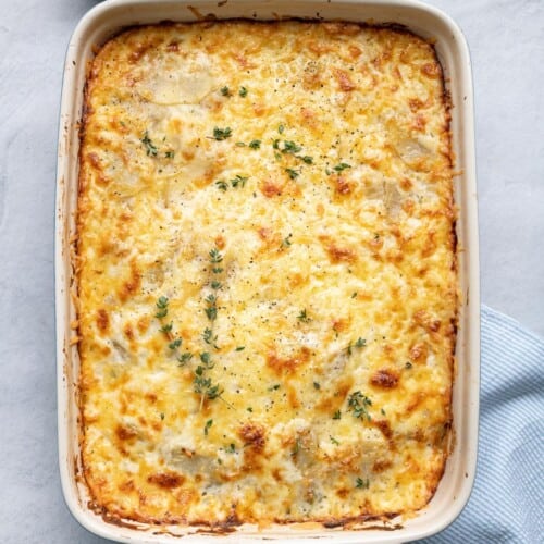 Scalloped potatoes after done baking garnished with fresh thyme leaves and black pepper.