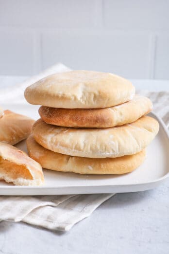 stack of freshly baked homemade pita bread on white square plate