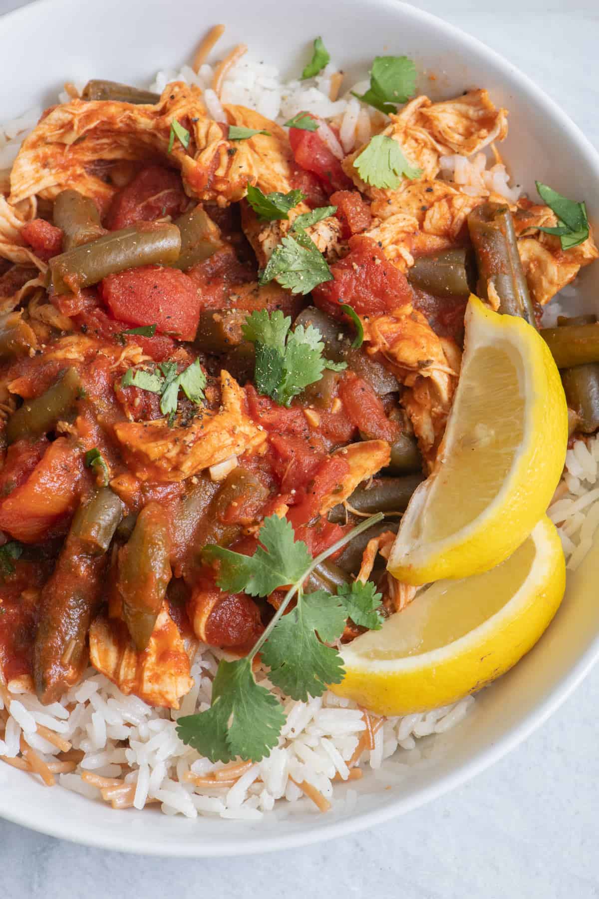 close up of Lebanese Green Bean Stew with 2 lemon wedges