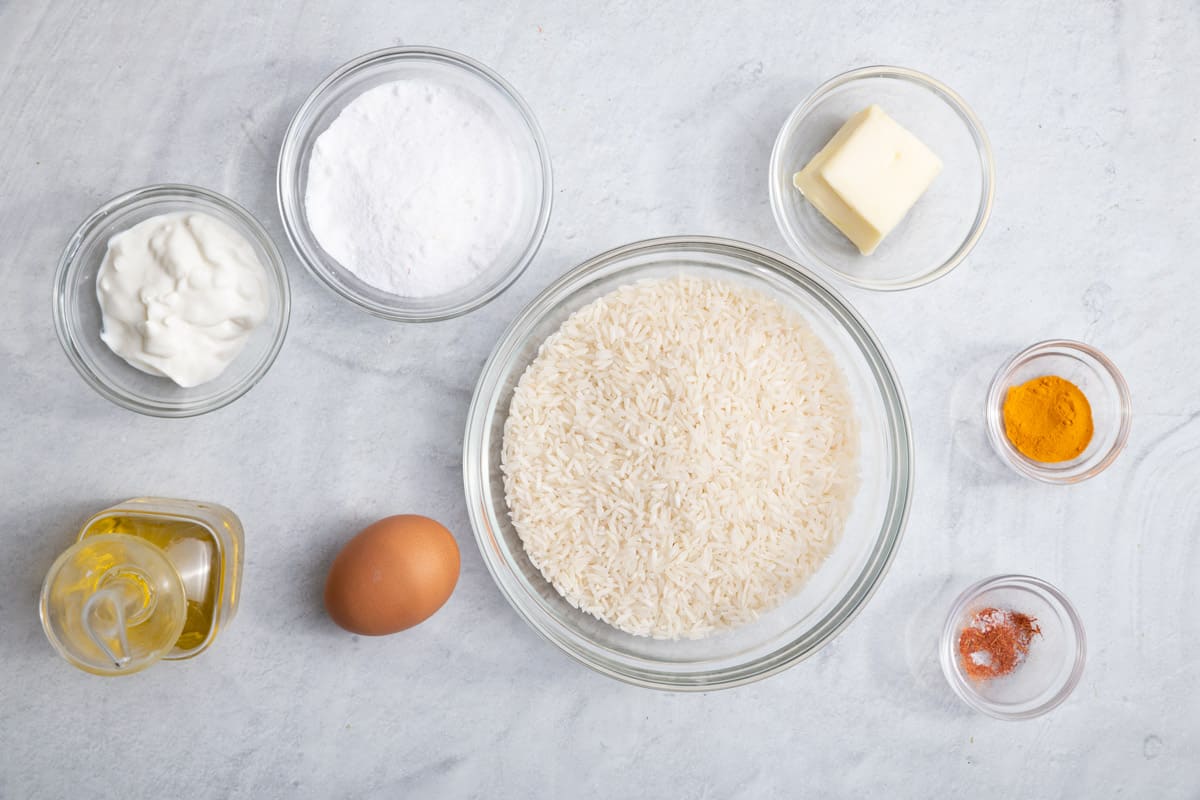 Ingredients for recipe in individual bowls: Greek yogurt, kosher salt, olive oil, 1 egg, basmati rice, butter, ground turmeric, and saffron threads