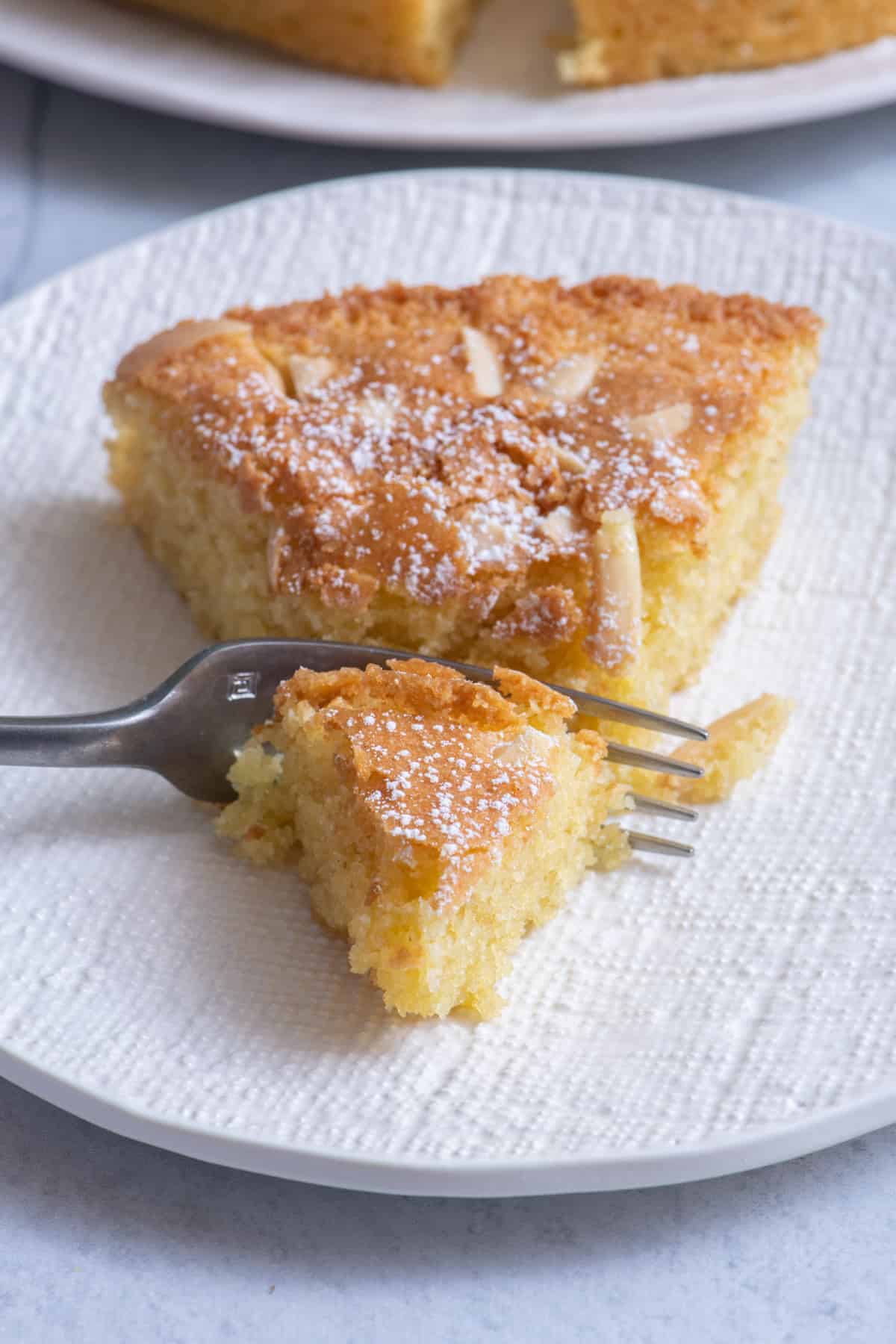 Small cake plate with one slice of cake with bite taken out on fork to show texture