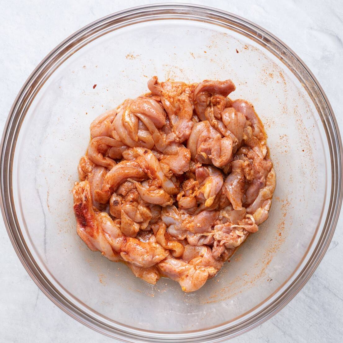 Seasoned raw chicken in a bowl.