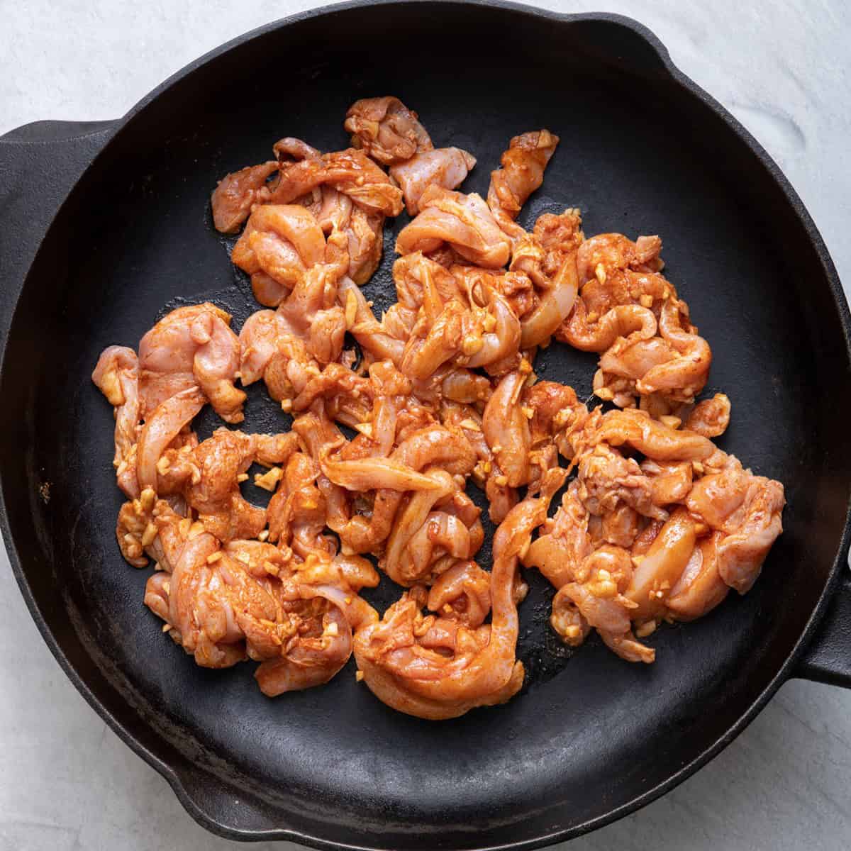 Raw chicken on a pan on the stove.