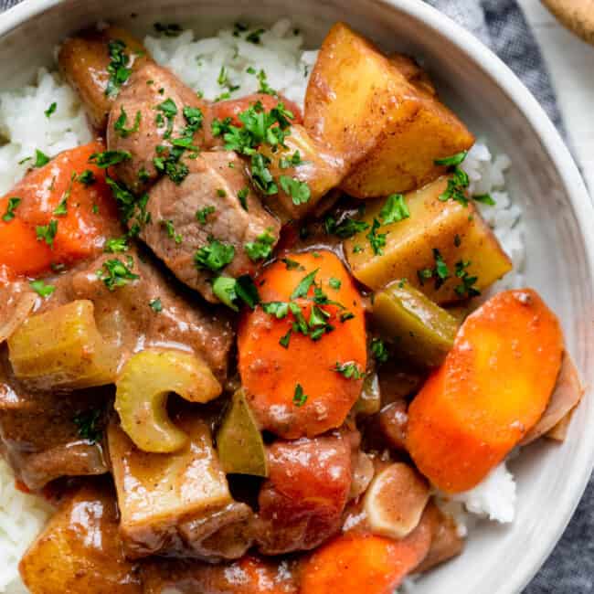 Bowl of oven roasted beef and vegetables over white rice in a white bowl.