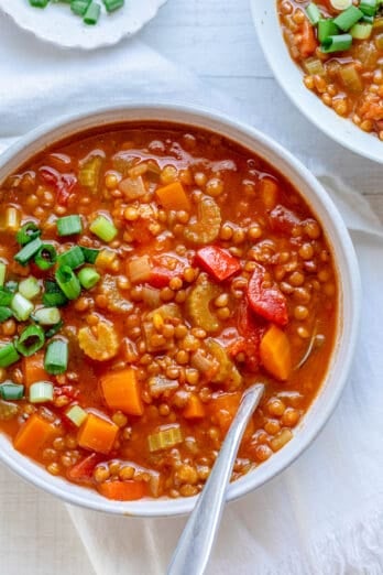 Bowl of tomato lentil soup garnished with green onions.