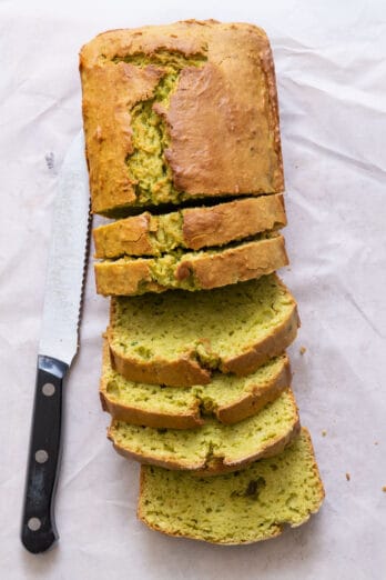 Top view of avocado bread with a few thick slices cut and knife off to side.