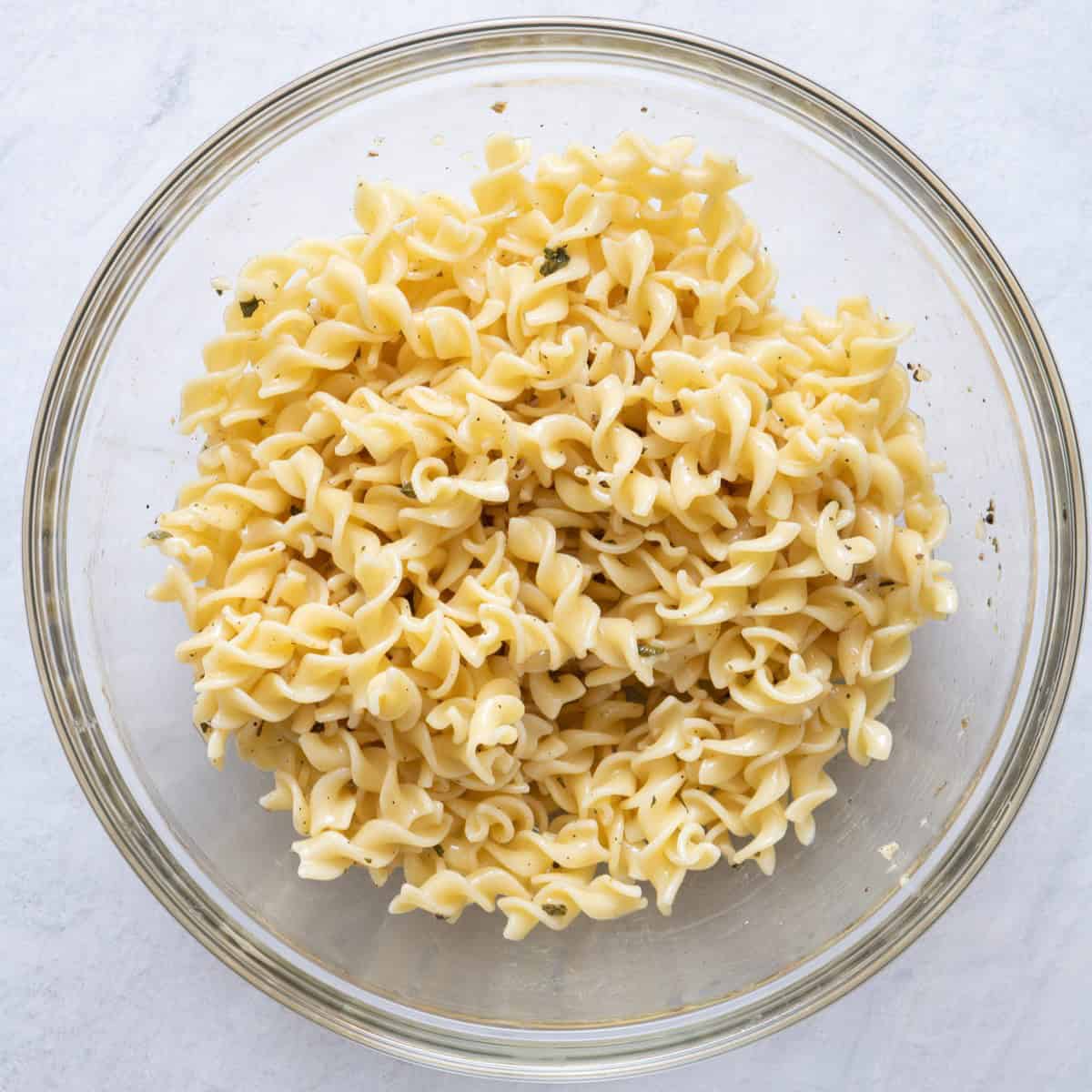 Cooked pasta added to the bowl of dressing.
