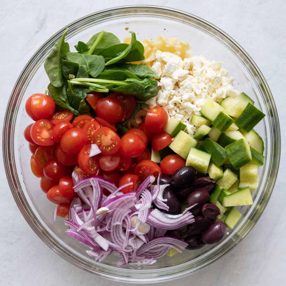The rest of the ingredients for the pasta salad added to the bowl of dressing and pasta.