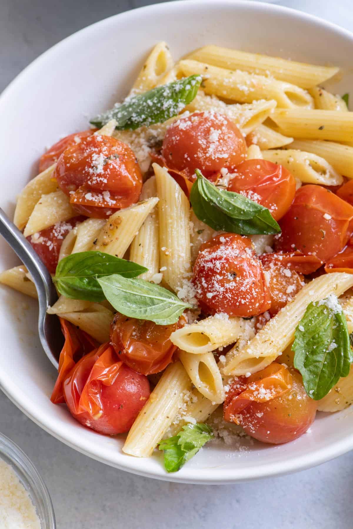 Close up of pasta recipe in white bowl with fork inserted into pasta.