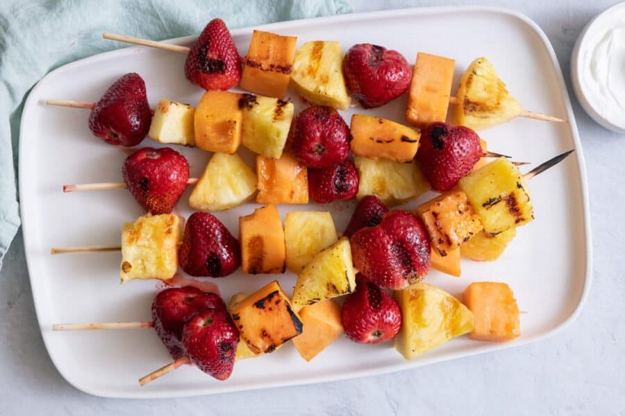 Grilled fruit kabobs laid flat on a serving dish.