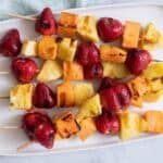 Grilled fruit kabobs laid flat on a serving dish.