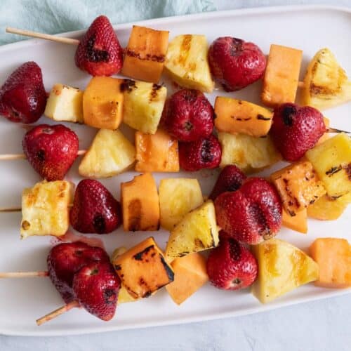 Grilled fruit kabobs laid flat on a serving dish.