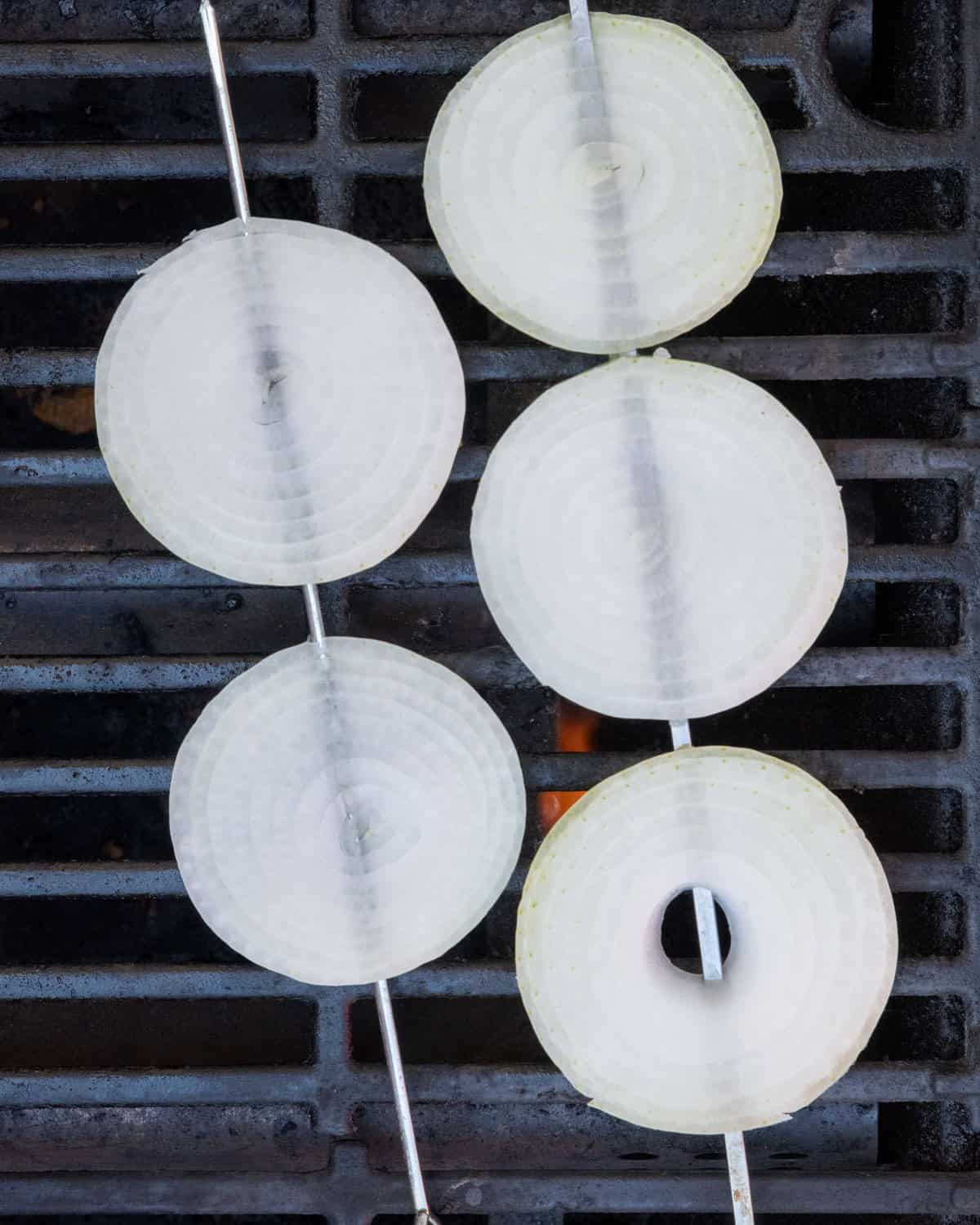 Onion slices on grill before grilling.