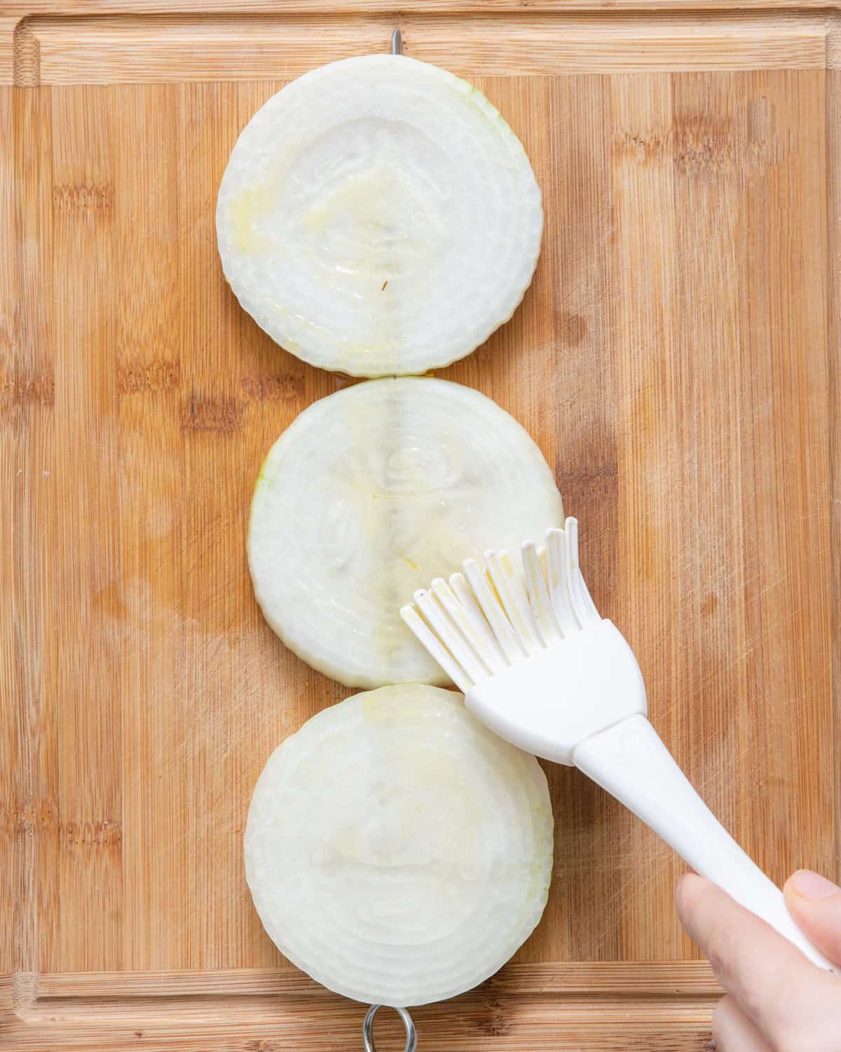 Brushing olive oil, salt and pepper on onion ring.