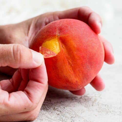 Peeling the peach beginning at the score.