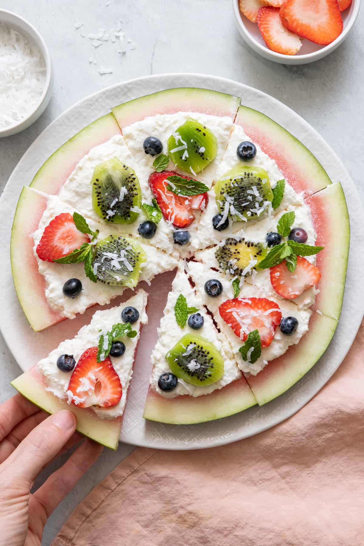 Overhead shot of watermelon pizza with a slice being removed.