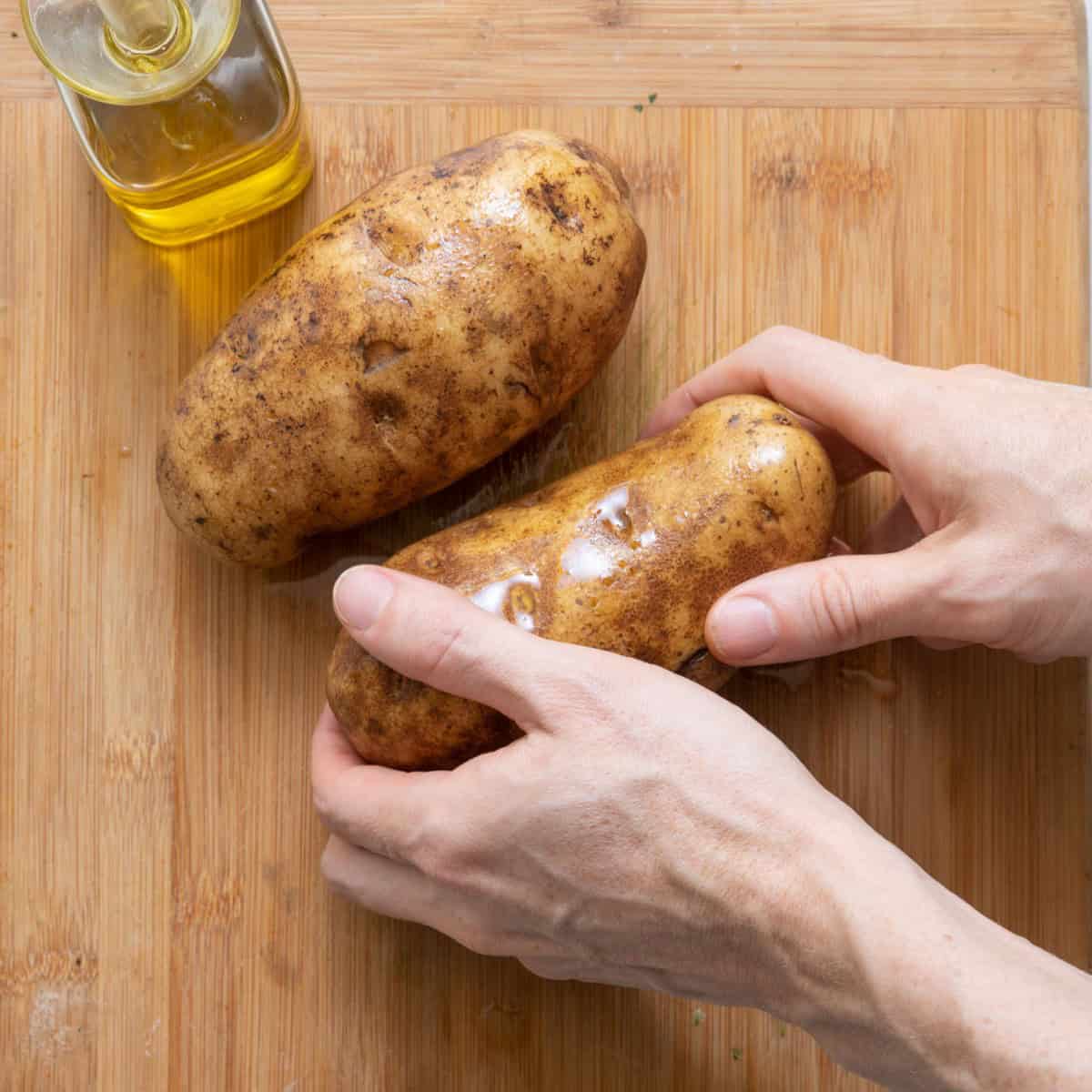Rubbing olive oil on potatoes.