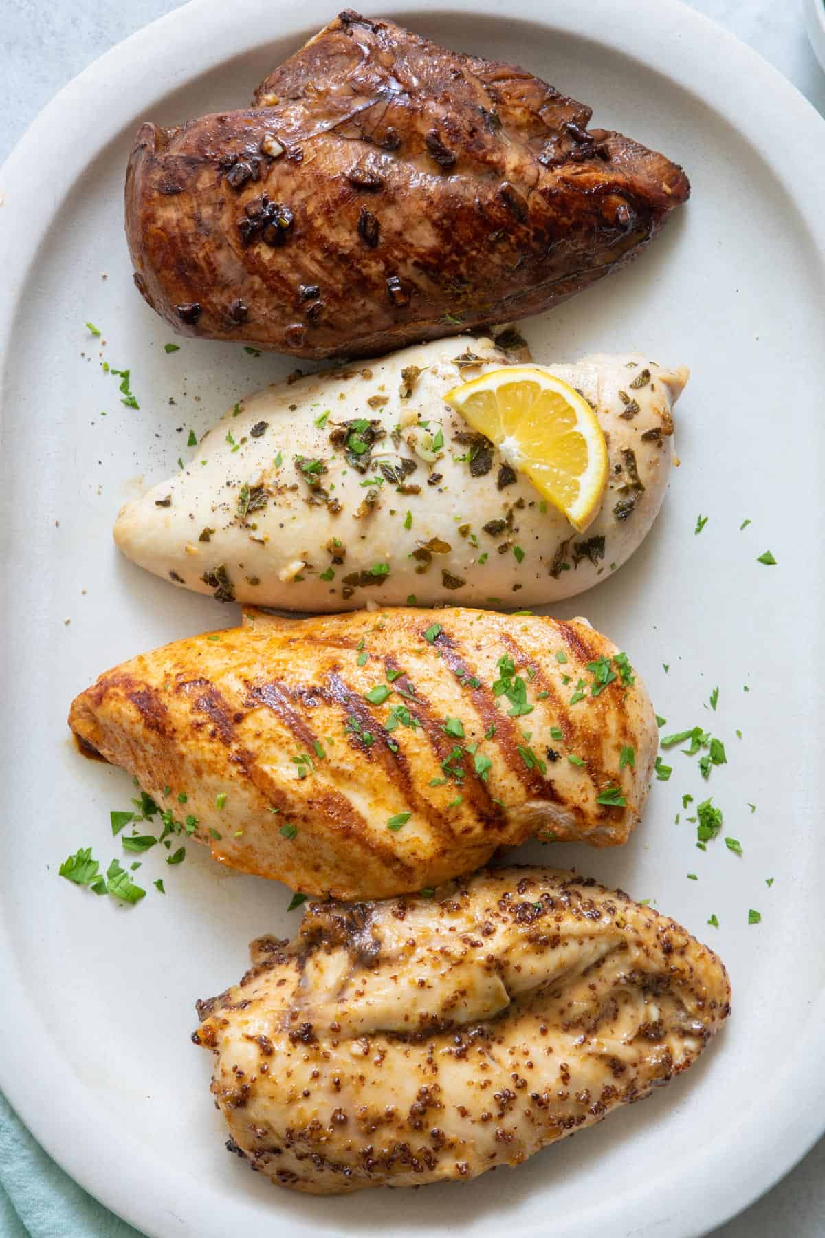 4 chicken breast that was marinated in different recipes and cooked garnished with parsley.