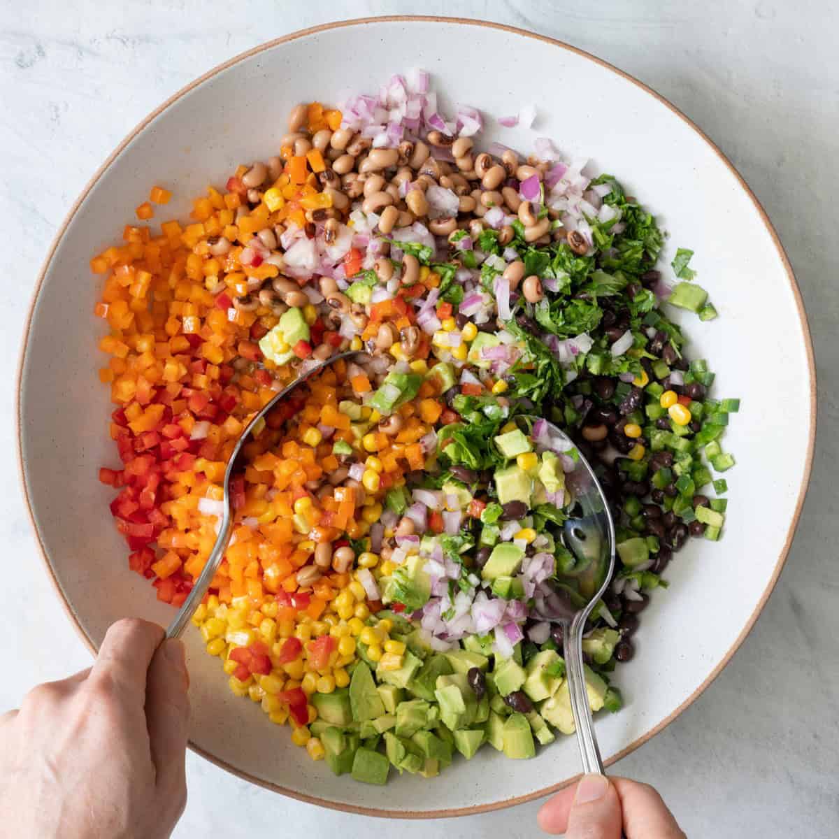 Tossing salad with large spoon.