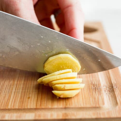 Slicing ginger with a sharp knife on a cutting board