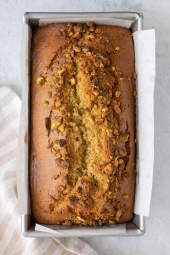 Overhead shot of pistachio bread baked in a loaf pan with parchment paper.
