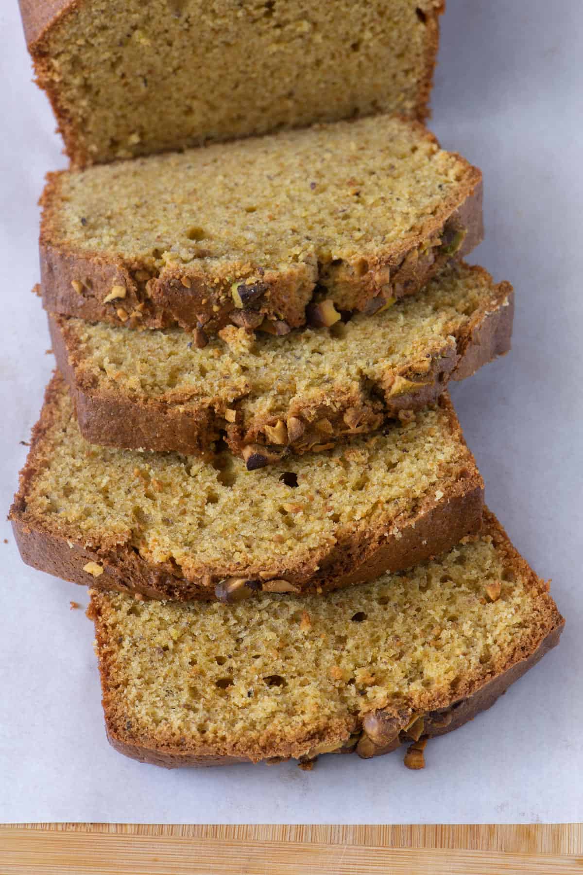 Close up of four thick slices of pistachio bread showing moist texture.