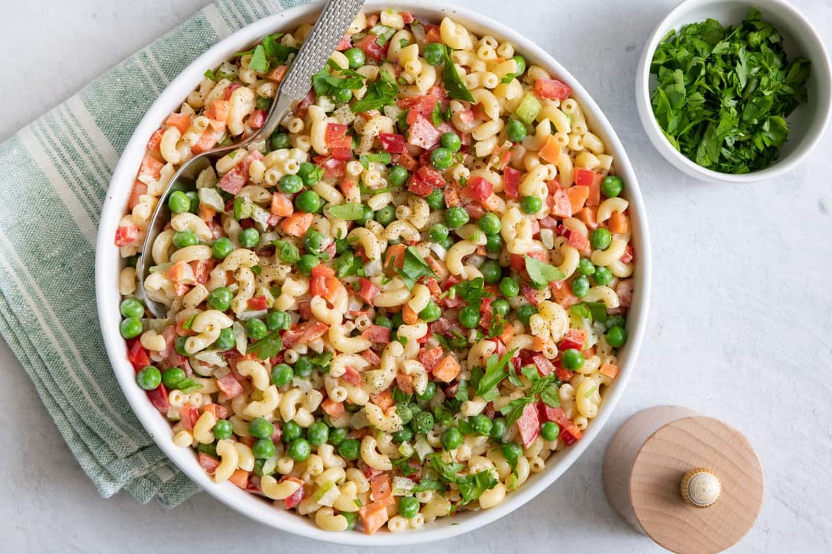 Large bowl of macaroni salad with large serving spoon inside.