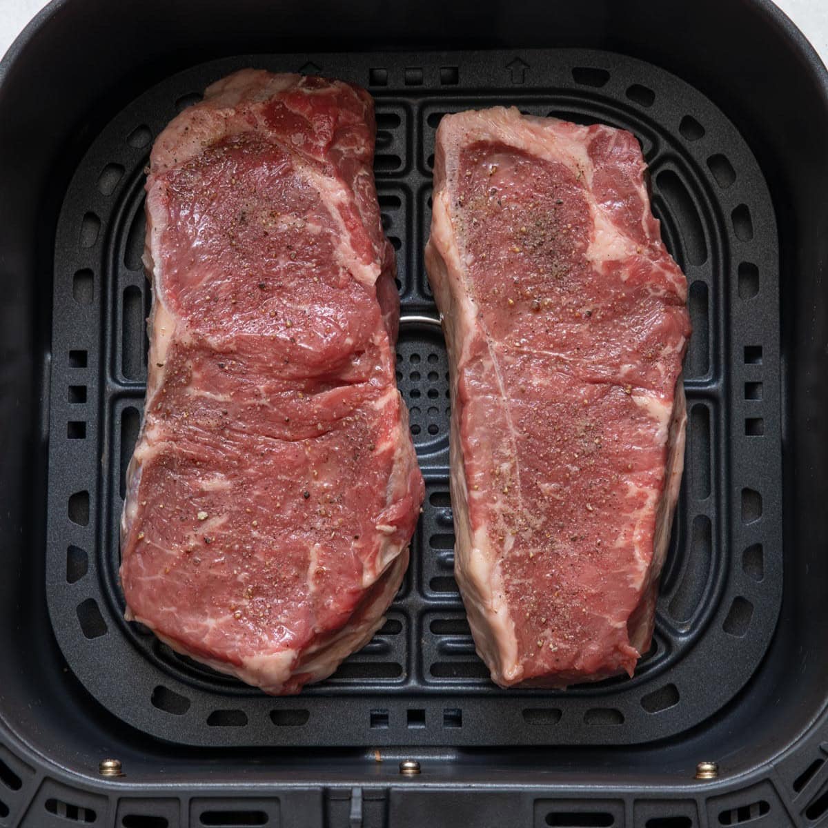 2 steaks in air fryer before cooked.