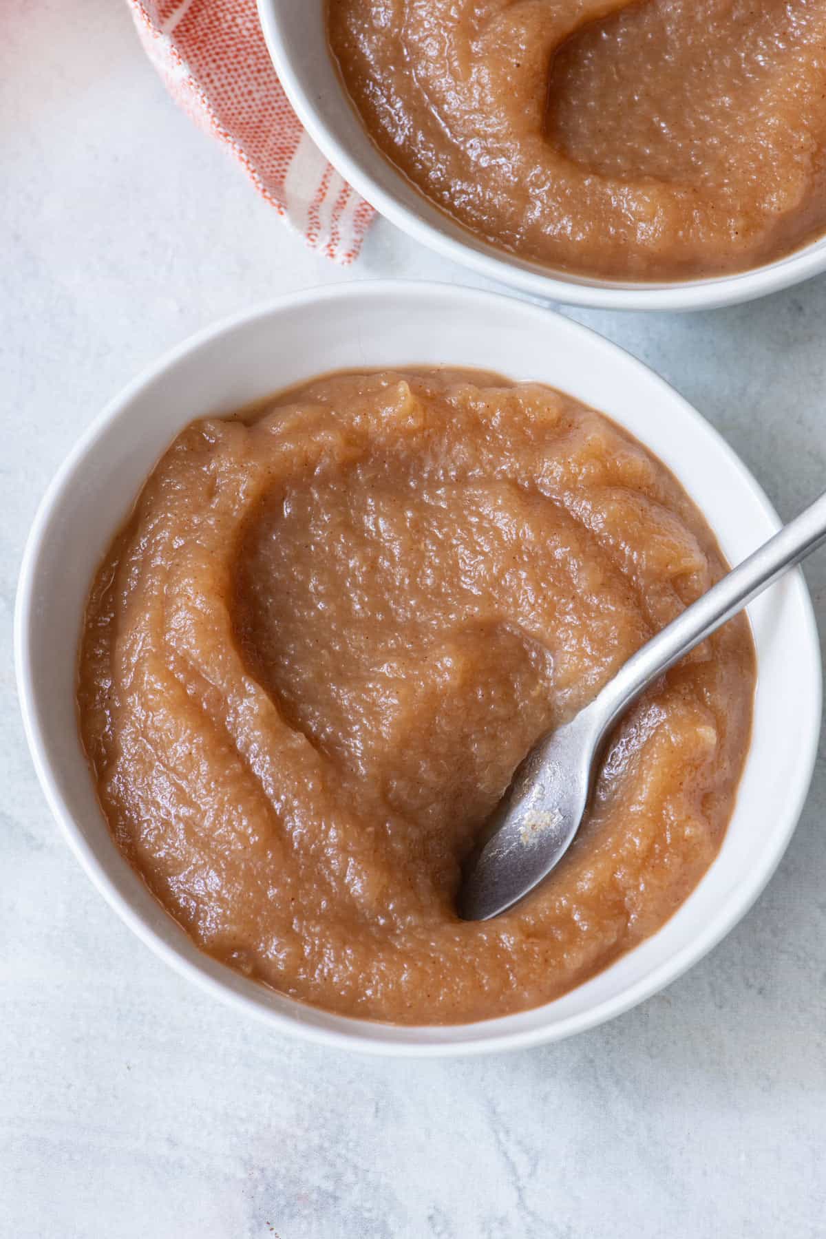 Small bowl with a spoon dipped into fruit butter.