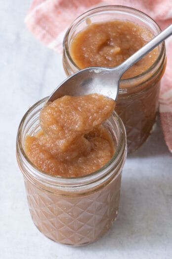 2 small glass jars with a spoon lifting some from the jar in foreground.
