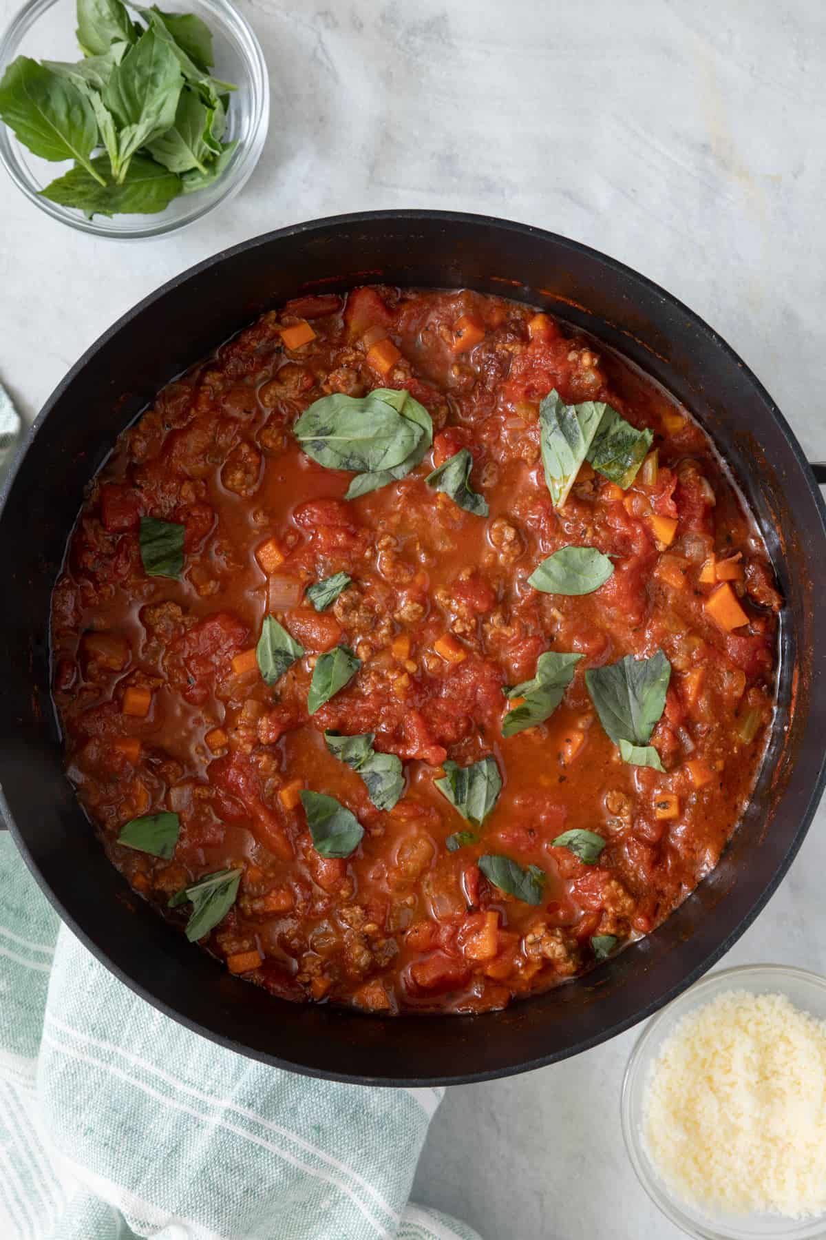Pot of spaghetti sauce garnished with fresh basil.