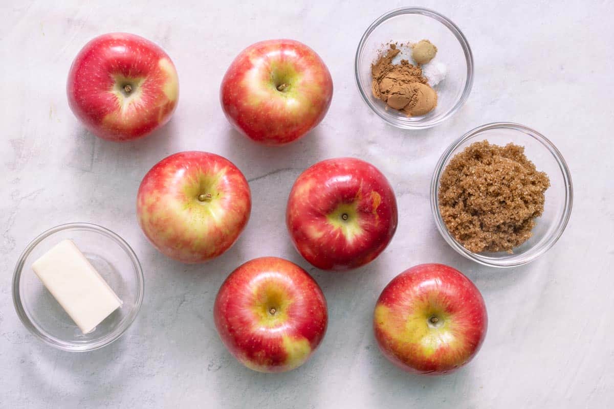 Ingredients for recipe before being prepped: butter stick, 6 whole red apples, spices, and brown sugar.