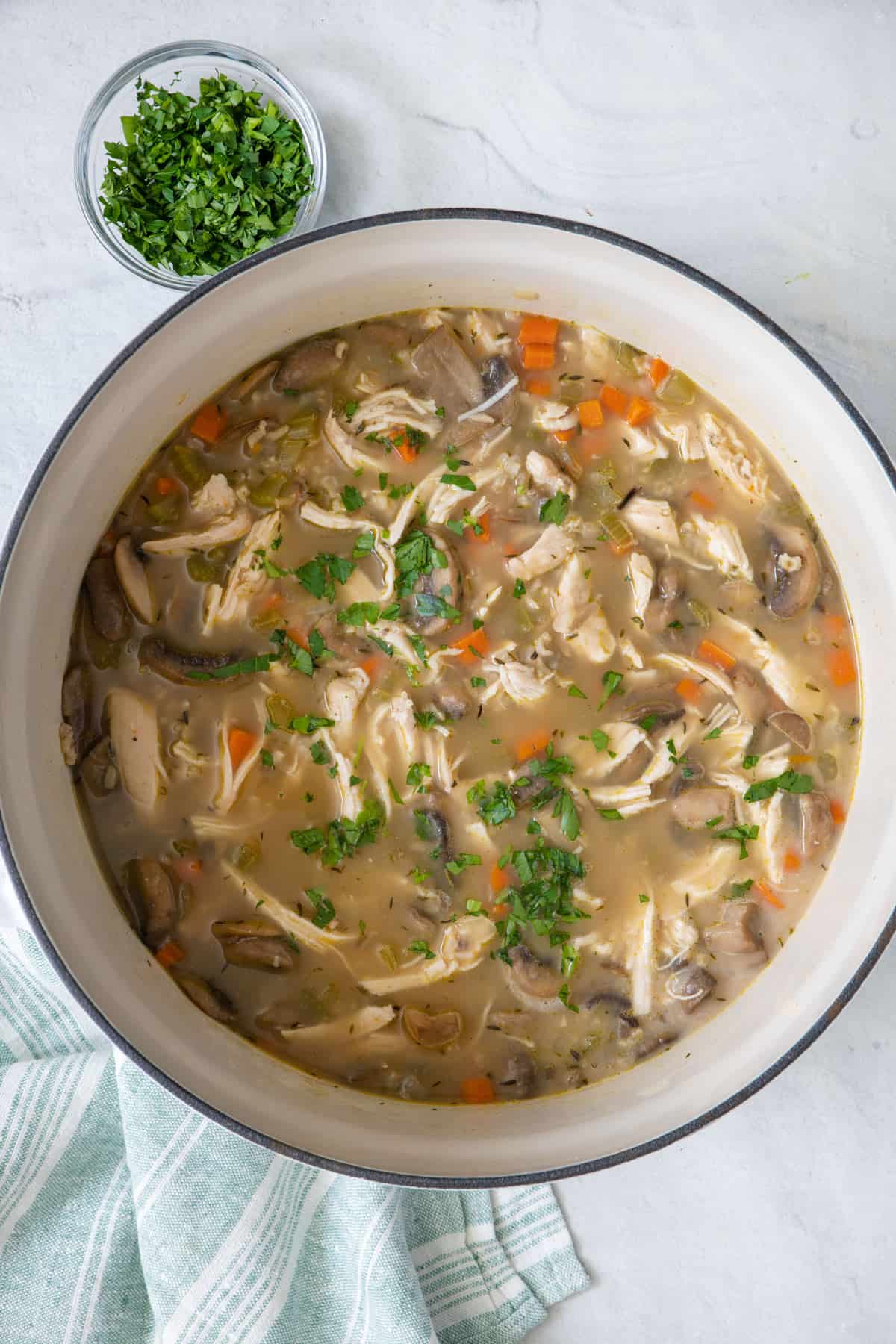 Overhead shot of chicken and rice soup in pot after cooking showing shredded meat and veggies throughout.
