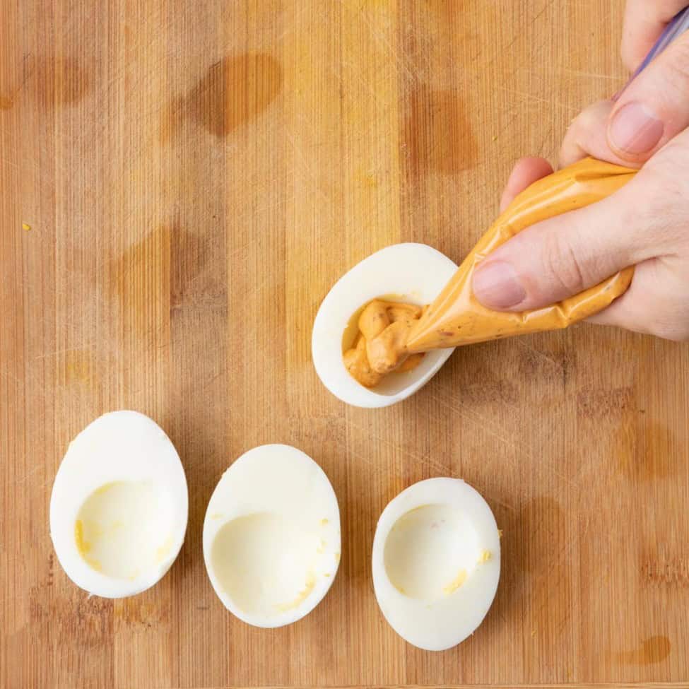Piping harissa eggs.